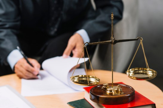 legal-adviser-signing-contract-with-justice-scale-foreground_23-2147898662